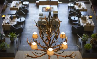 a chandelier hangs from the ceiling in a room with couches and tables , creating an inviting atmosphere at Kempinski Hotel Berchtesgaden