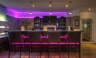 a modern bar with a purple neon light , black chairs , and multiple bottles of alcohol on display at Lindenhof