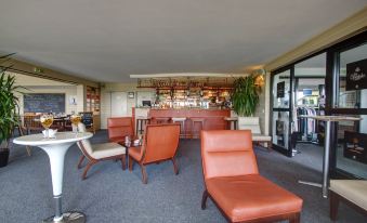 a cozy living room with orange couches and chairs , along with a bar area in the background at Hotel du Golf