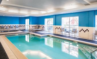 an indoor swimming pool with blue walls and white tiles , surrounded by lounge chairs and umbrellas at Sonesta Select Seattle Renton Suites