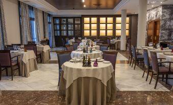 a large , well - lit restaurant with multiple dining tables and chairs , all set for a meal at Castilla Termal Solares