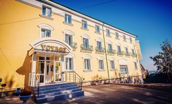 "a large yellow building with the word "" voyagy "" written on it , located in a city" at Voyage Hotel