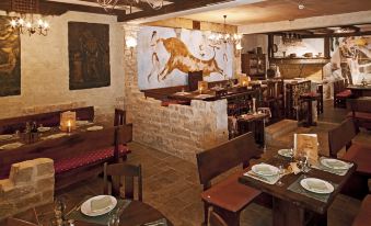 a restaurant with wooden tables and chairs , a bar area , and a painting of a cow on the wall at Bluesun Hotel Elaphusa