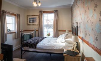 a cozy bedroom with a wooden bed , a window seat , and a lamp on the nightstand at The Forth Inn