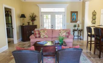 a living room with a pink couch , wooden coffee table , and two chairs , along with two doors leading to another room at Concord Inn