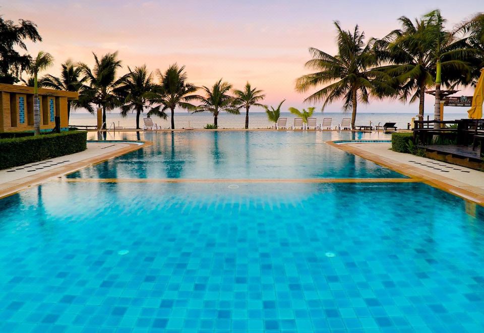 a large swimming pool with blue tiles is surrounded by palm trees and a beach at Chaolao Cabana Resort