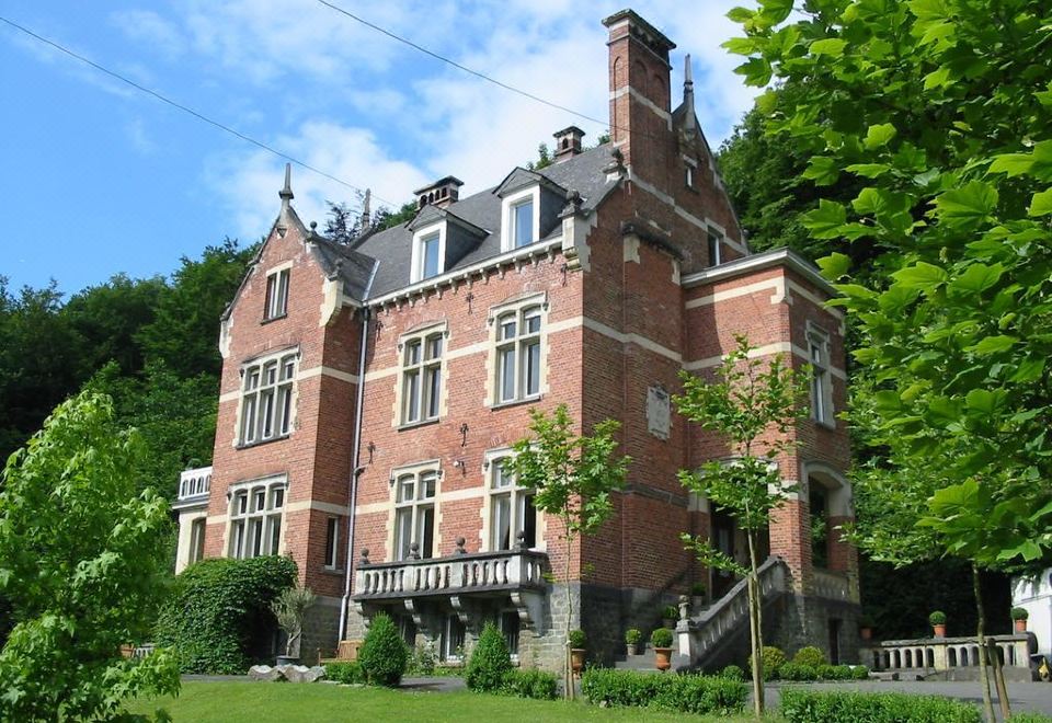 a large brick building surrounded by trees , with a lawn in front of it and a staircase leading up to the entrance at New-Castle