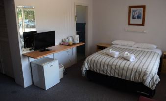 a hotel room with a bed , desk , and television , along with various amenities such as towels and beverages at Mount Beauty Motor Inn