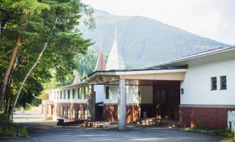 a white building with a red roof , surrounded by trees and mountains in the background at Arcadia