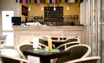a cozy coffee shop with several tables and chairs , along with a bar area filled with various beverages at Oxford Hotel