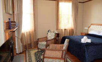 a cozy bedroom with two chairs , a table , and curtains , providing a comfortable living space at Left Bank