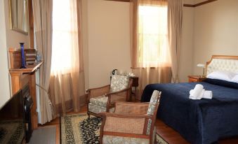 a bedroom with a bed , chair , and lamp is shown with sunlight coming in through the window at Left Bank