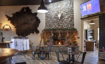 a cozy restaurant with a stone fireplace , wooden tables , chairs , and a large framed picture on the wall at OK Corral