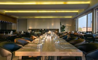 a long wooden dining table surrounded by chairs in a restaurant setting , with numerous people seated at it at Gaye City Hotel