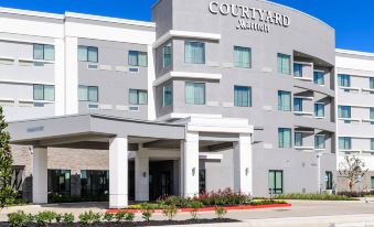 a large , modern hotel building with multiple stories and a courtyard marriott logo on the front at Courtyard Lake Jackson