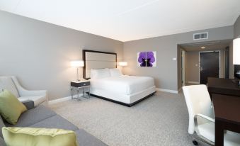 a large , white bed with a headboard is in the middle of a room with a couch and lamp at Holiday Inn Wilmington