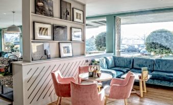 a modern living room with pink chairs , a couch , and a tv mounted on the wall at Holiday Inn Ipswich