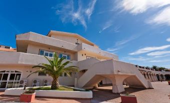 a modern , white building with a curved roof and a palm tree in front of it at La Plage Resort