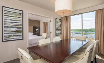 a dining room with a large wooden dining table surrounded by chairs , and a view of the ocean through a window at Sheraton Suites Chicago Elk Grove