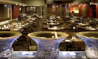 a large dining room with multiple tables and chairs , some of which are set up for a banquet at Mercure Sydney Liverpool