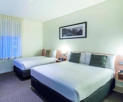 a hotel room with two beds , one on the left and one on the right side of the room at Ibis Melbourne Hotel and Apartments