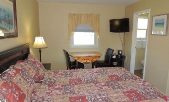 a hotel room with a king - sized bed , a flat - screen tv , and a dining table with chairs at The Clipper Inn