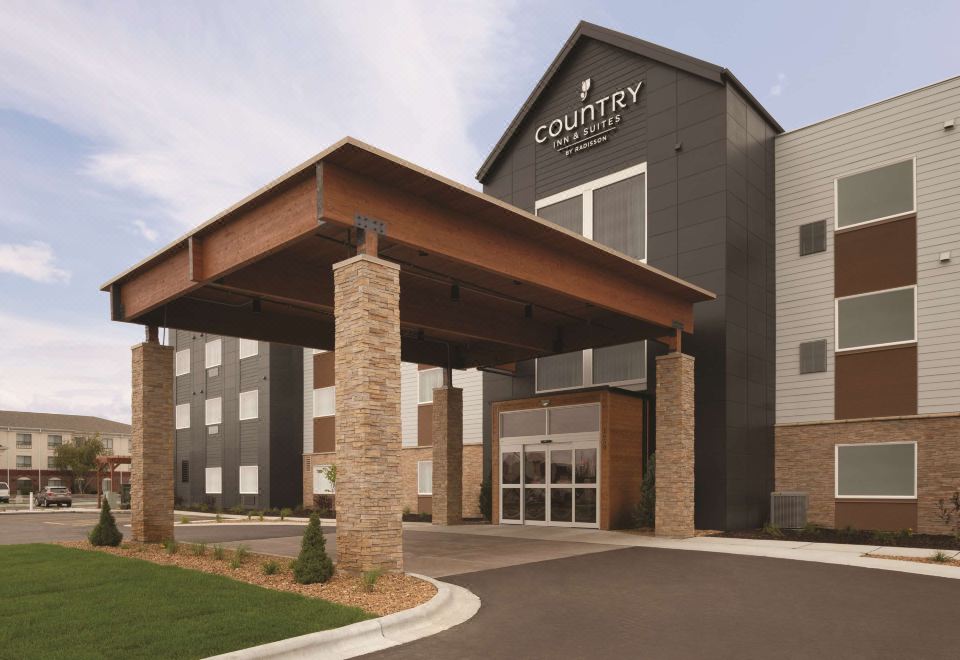a modern hotel building with a covered entrance , surrounded by trees and a clear sky at Country Inn & Suites by Radisson, Ft. Atkinson, WI
