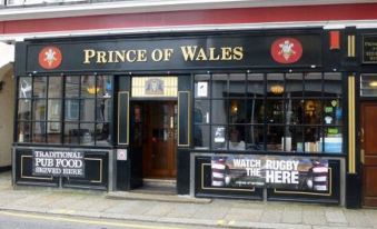 "a building with a black and red sign that reads "" prince of wales "" prominently displayed on the front" at Prince of Wales