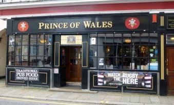 "a building with a black and red sign that reads "" prince of wales "" prominently displayed on the front" at The Prince of Wales Pub