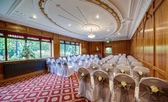 a well - decorated banquet hall with rows of chairs arranged in a semicircle , ready for a wedding ceremony at Bredbury Hall Hotel