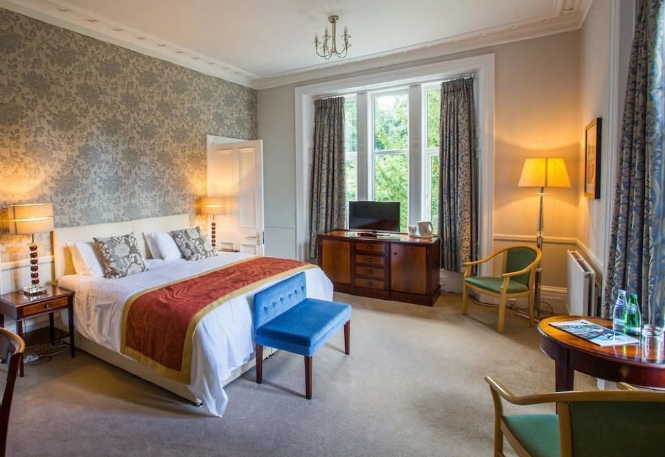 a well - decorated hotel room with a large bed , blue and white furniture , and a television at Balcary House Hotel