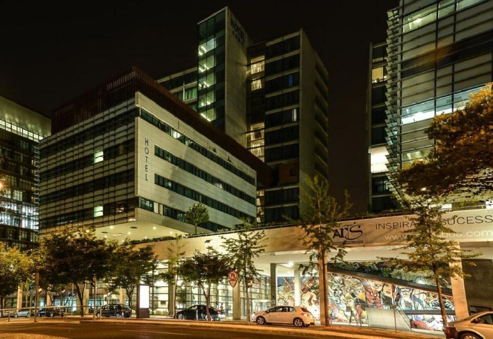 At night, there is a cityscape with a building in the foreground and an office tower rising behind it at VIP Executive Arts Hotel