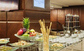 a buffet table with a variety of appetizers , including fruit , crackers , and other snacks , as well as a television at DoubleTree by Hilton Istanbul-Avcilar