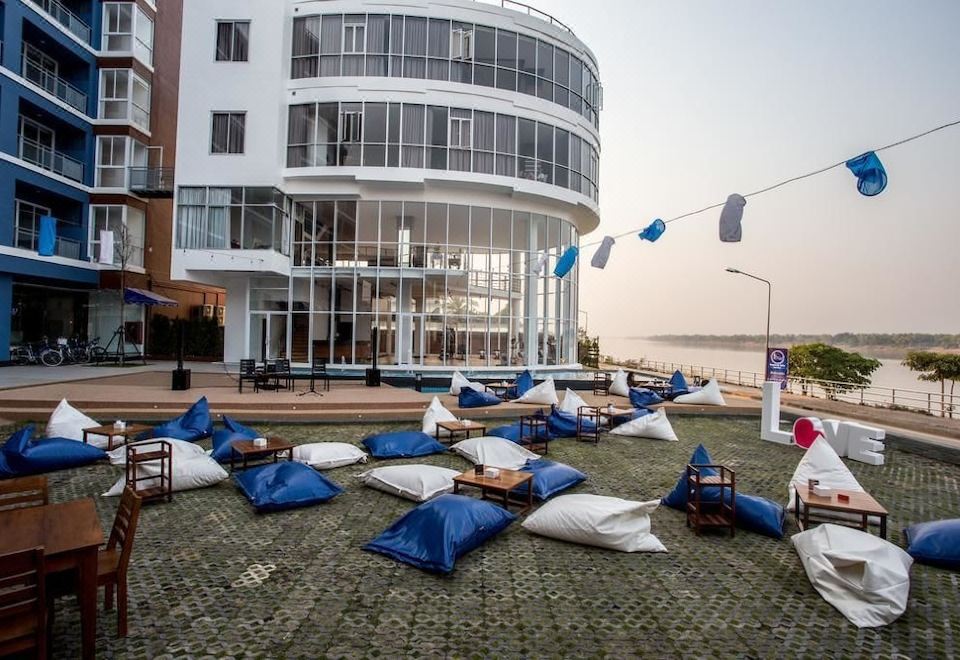 a large white building with multiple floors and balconies , surrounded by a grassy area filled with bean bag chairs at Blu Hotel