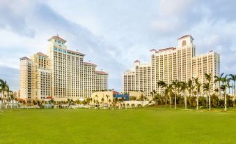 a large green field with palm trees and a large building in the background , possibly a hotel or a resort at Grand Hyatt Baha Mar