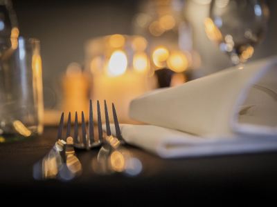 a table setting with a fork and knife , napkins , and candles in the background , with lights from the same lights behind at Ibis Melbourne Hotel and Apartments