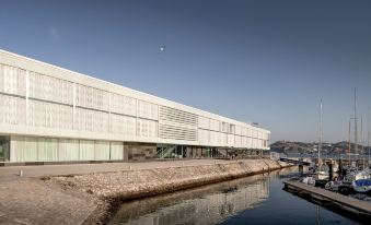 a large white building situated on the edge of a body of water , with a boat docked nearby at Altis Belem Hotel & Spa, a Member of Design Hotels