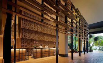 a modern building with an open - air structure , featuring a reception area and two people behind the counter at PARKROYAL Penang Resort