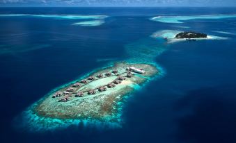 aerial view of a tropical island with several small islands and blue water in the ocean at Raffles Maldives Meradhoo Resort