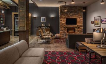 a living room with a brick wall , wooden floor , and several chairs arranged around a coffee table at Four Points by Sheraton Juneau