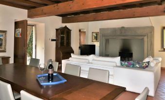 a dining room with a wooden table and chairs , white couches , and a fireplace in the background at Villa