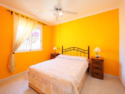 a bedroom with a yellow wall and a bed , featuring two nightstands on either side of the bed at Joli Joli Photo