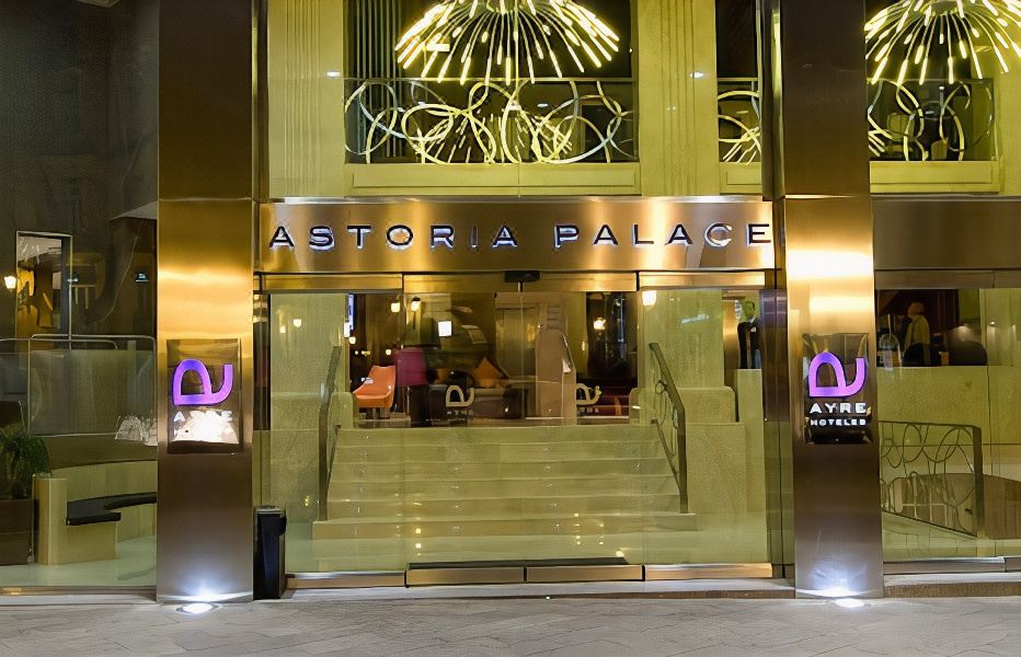 "the entrance of a building named "" astor palace "" with a gold - colored sign above the entrance and people walking up the stairs" at Only You Hotel Valencia