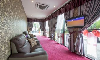 a living room with a large flat screen tv mounted on the wall , a couch , and a chair at Hamilton Hotel Kajang