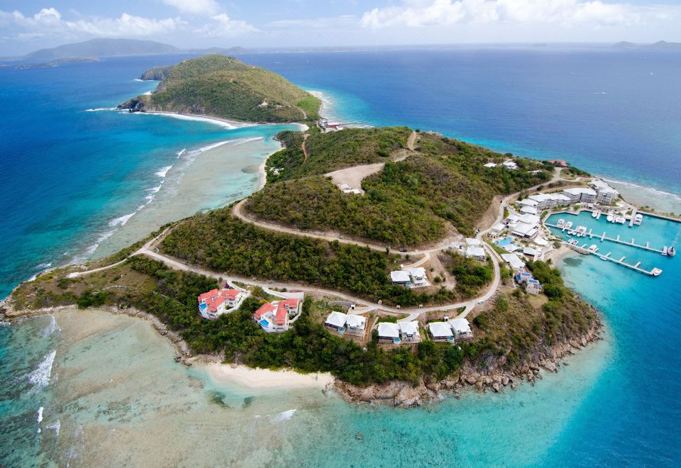 a bird 's eye view of a tropical island with houses , roads , and palm trees on the coast at Scrub Island Resort, Spa & Marina