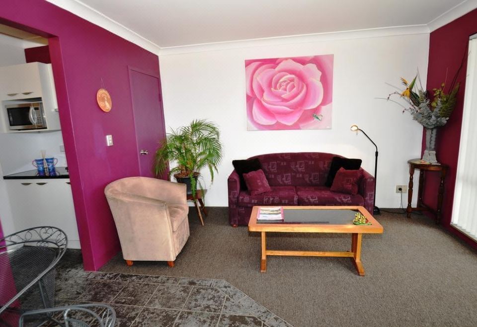 a living room with a purple couch , a chair , and a painting on the wall at Beachfront Apartments