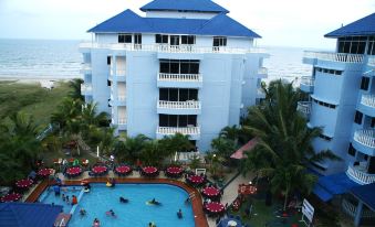 a large blue building with a swimming pool and palm trees in front of it at Sanctuary Resort