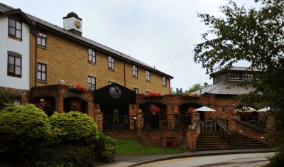 a brick building with a clock tower on the side , surrounded by a courtyard with potted plants at Village Hotel Liverpool