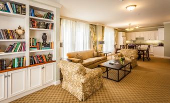 a living room with a couch , chairs , and a bookshelf filled with books , creating a cozy and inviting atmosphere at Royal Park Hotel