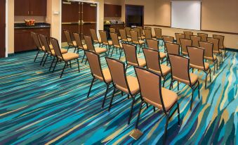 a conference room with rows of chairs arranged in a semicircle , and a projector screen mounted on the wall at SpringHill Suites Cleveland Solon